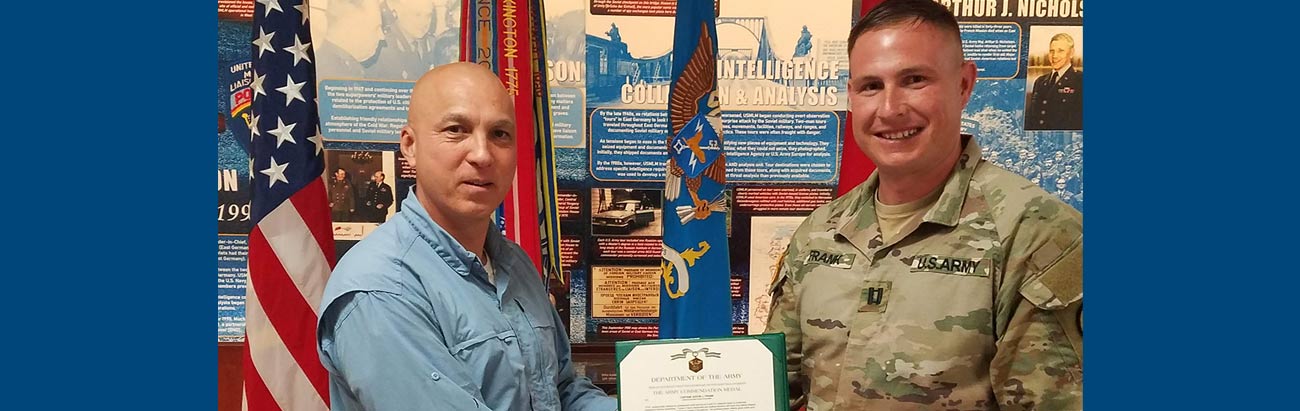 CPT Justin Frank receives an Army Commendation Medal from Mr. Pete Don, SES, USAICoE, Fort Huachuca for his thesis using VR to train intel analysts.